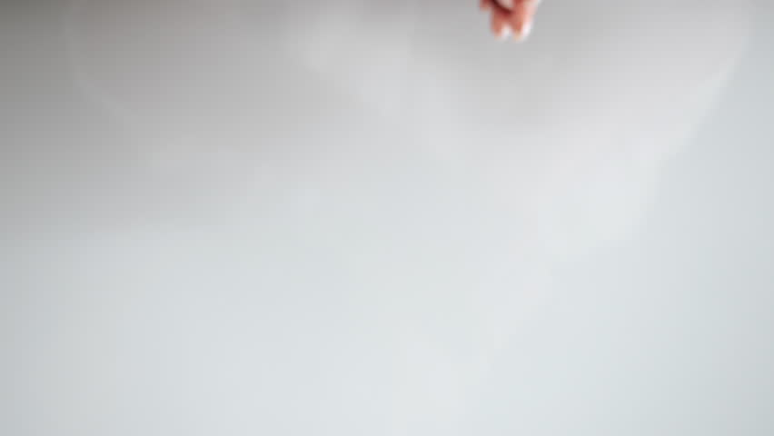 Close up of woman opening hands and showing green supplement tablets in palms isolated on light background in indoor setting.