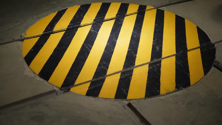Round danger zone sign on the floor. Yellow-black warning sign in the industrial safety zone inside the factory. Warning strips. Zone of caution and attention.