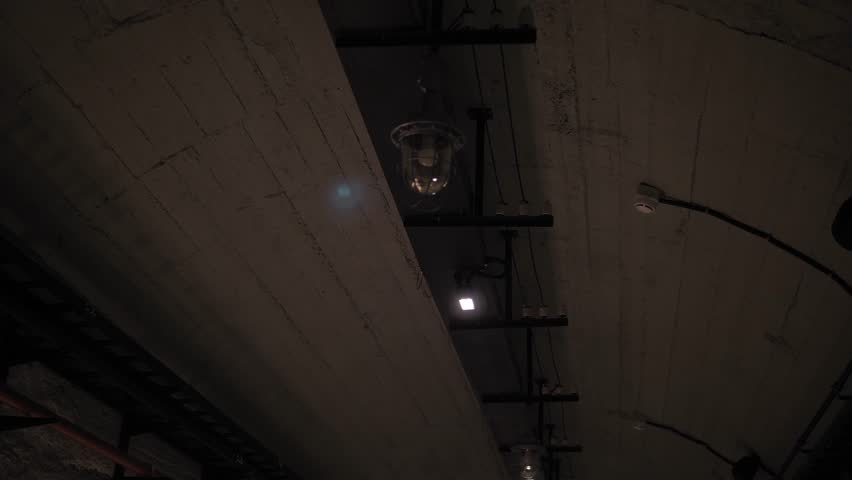 A long winding tunnel with old lamps and wires. A dark corridor with flashing and broken lamps on the ceiling, a creepy place underground - catacombs. Nuclear war, bomb shelters, an underground tunnel