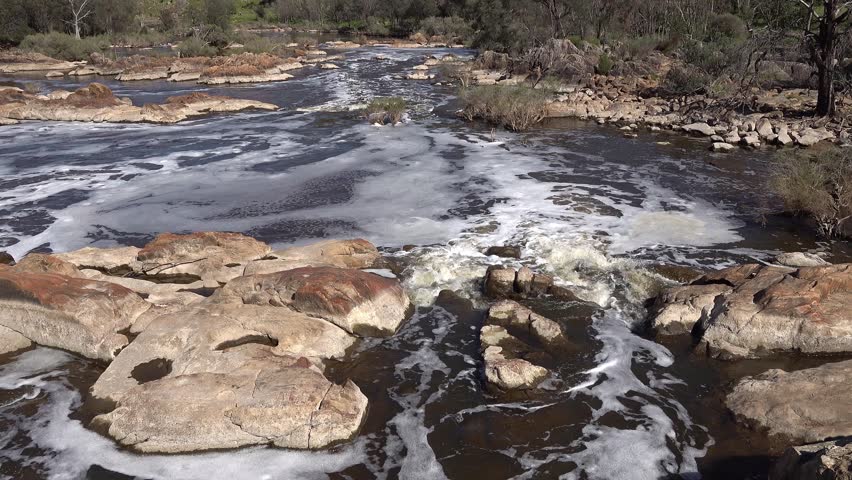 Powerful River Rapids with White Foam Flowing Over Ancient Rocks