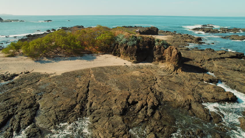 Rocky coastal cliffs with flag of Costa Rica surrounded by turquoise ocean waves