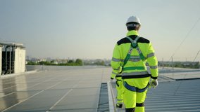 Two engineers in safety gear and harnesses inspect solar panels on a commercial rooftop during sunset. Professional maintenance of renewable energy systems for sustainable industrial power solutions. - Powered by Shutterstock - Get 15% off with code: PIKWIZARD15