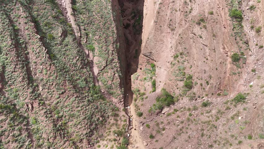 Aerial view of majestic red rock mountain formations with green vegetation under a cloudy sky.
