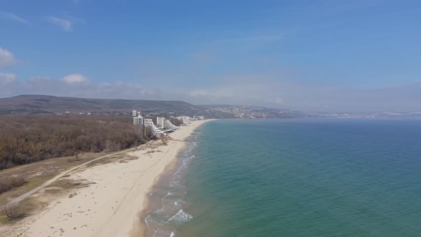 Aerial shot of coastline with beach and turquoise sea under sunny sky