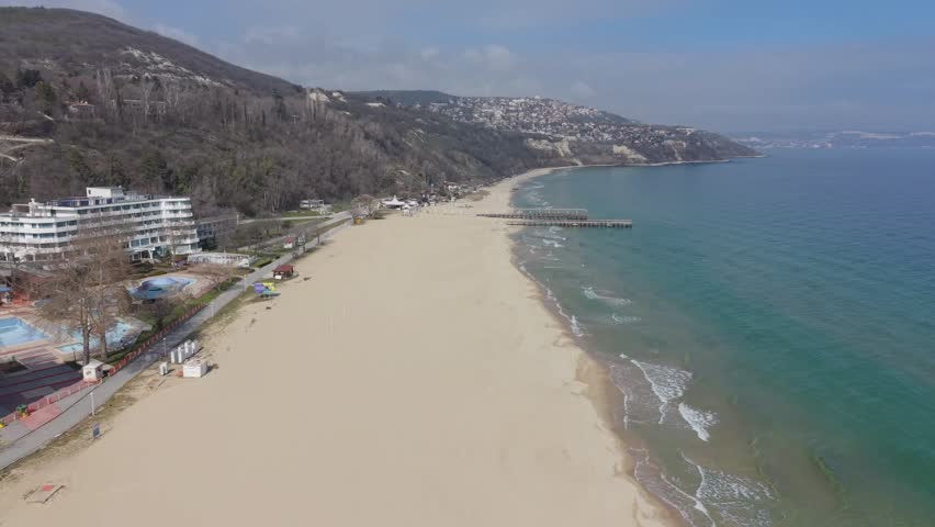 Aerial view of coastal landscape with beach and sea under bright sky