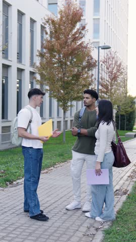 group of young college students standing together outside the university building, actively discussing their school projects