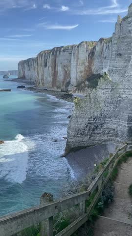 Etretat chalk cliffs coastal path with wooden fence overlooking turquoise Atlantic ocean dramatic landscape in Normandy France