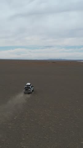 Vehicle Leaves Marks On Vast Plain. An Isolated Vehicle Explores Vast Barren Terrain During Aerial Pursuit. Lone Car Creates Dust Trail Across Expansive Flatlands In Adventure Expedition