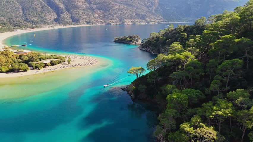 Spectacular aerial view of Blue Lagoon in Oludeniz, Turkey, crystal clear turquoise water meets sandy beach. Camera flies forward showing lush green mountains surrounding the bay in Oludeniz, Turkey