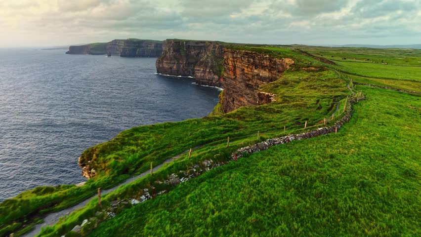 Aerial view of the Cliffs of Moher, Ireland. Drone flies along Cliffs of Moher landscape in Ireland with emerald green fields meet the crashing waves of the Atlantic Ocean