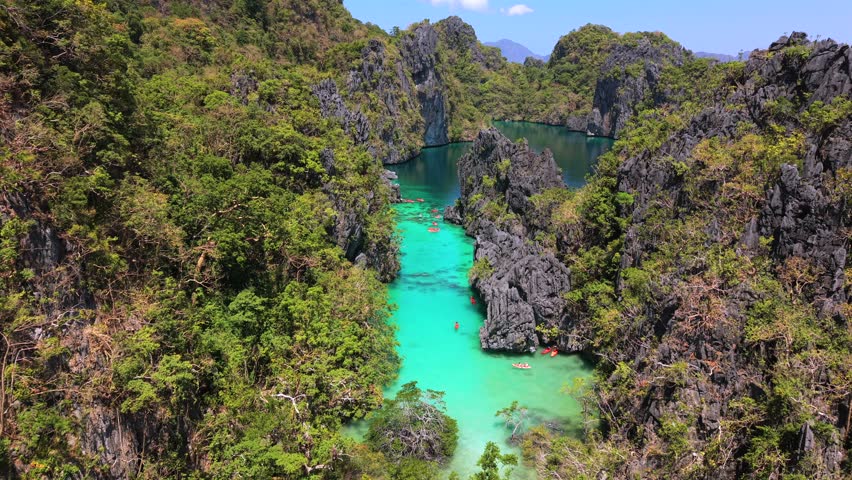 Aerial drone view of Big Lagoon in El Nido, Palawan, Philippines, with turquoise water, limestone cliffs, and kayaks exploring a hidden tropical paradise.