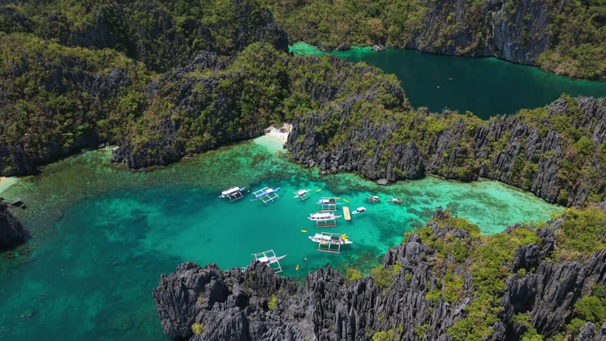 Aerial drone view of Big Lagoon and Small Lagoon in El Nido, Palawan, Philippines, featuring turquoise water, limestone cliffs, and traditional boats in a famous tropical island paradise.