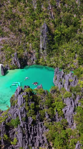 Aerial drone view of Cadlao Lagoon in El Nido, Palawan, Philippines, with turquoise water, limestone cliffs, and boats in a secluded tropical paradise.