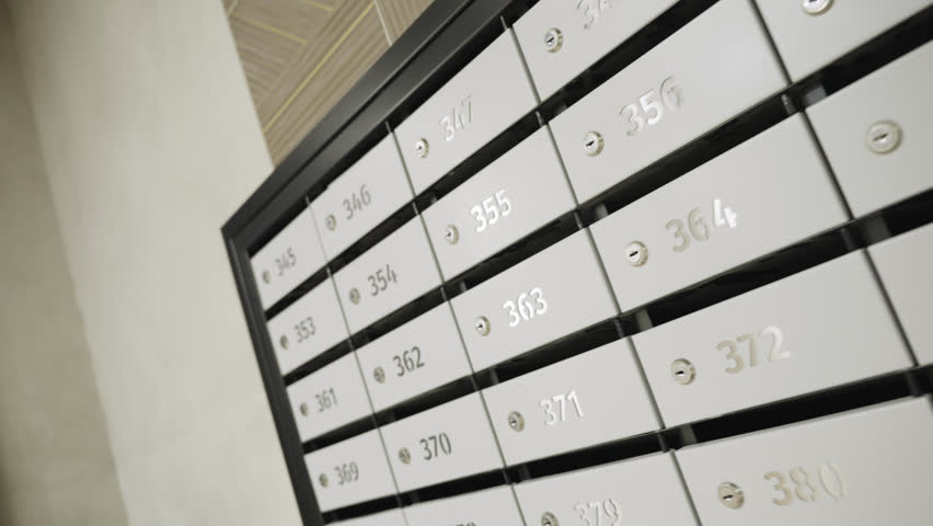 Metal chest with mail boxes and apartment numbers in hallway of condominium building. Modern postboxes for tenants letters receiving