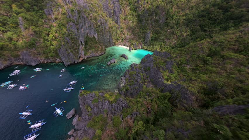 Cinematic FPV drone flight over Cadlao Lagoon in El Nido, Palawan, Philippines, with turquoise water, limestone cliffs, and boats in a hidden tropical paradise.