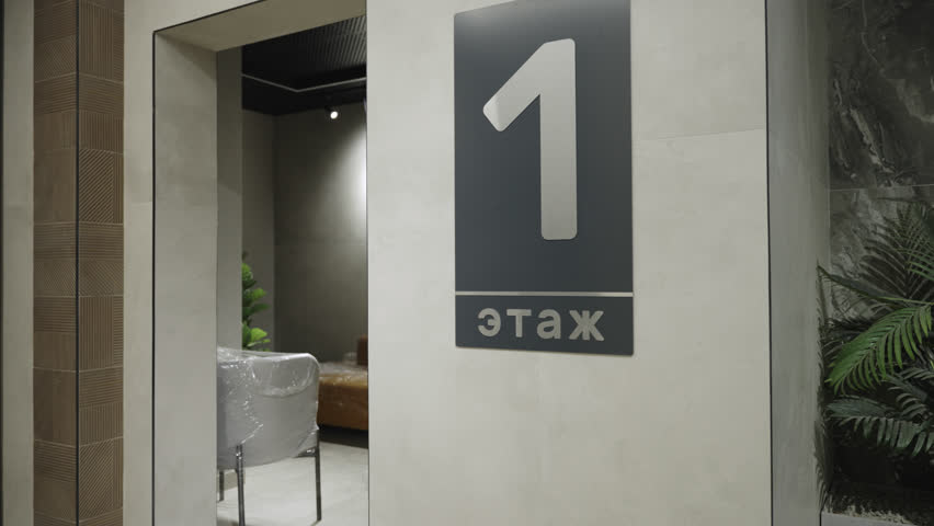 First floor sign on grey wall in minimalist office center design. Information for public center visitors in lobby. Building level number