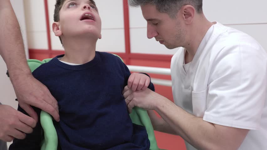 Healthcare professionals fitting a custom vacuum cushion on a boy with a disability. Orthopedic specialists molding the support for comfort