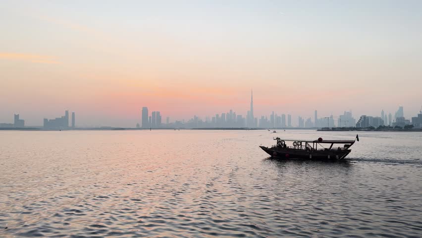 Traditional dhow boat and skyline of Dubai at sunset, United Arab Emirates