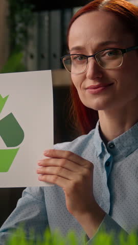Smiling Caucasian business woman eco activist showing recycling sign sorting paper in office female businesswoman looking at camera environment care green energy climate protection reuse bio ecology