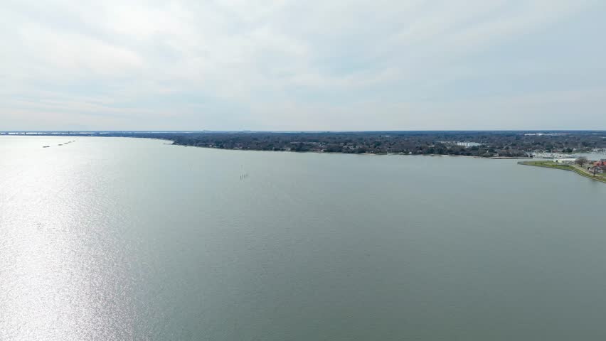 Chesapeake Bay coastline in Hampton Virginia, featuring the expansive blue waters of the estuary meeting the suburban shoreline on a clear spring day. 4k wide angle aerial video.