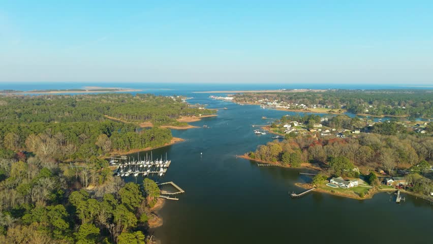 Aerial video of the York River coastline in Yorktown, Virginia, featuring lush green forests, residential docks, and calm blue water stretching toward the horizon.