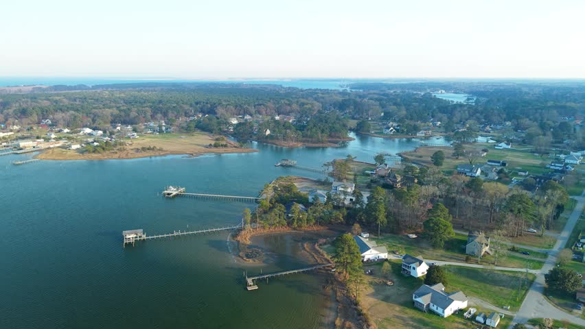 Aerial video of the York River coastline in Yorktown, Virginia, featuring lush green forests, residential docks, and calm blue water stretching toward the horizon.