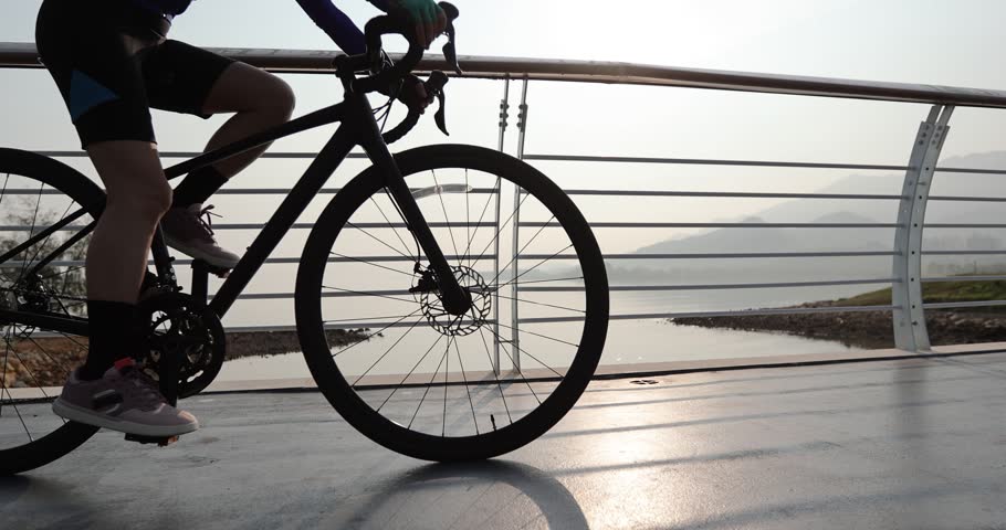 Fitness woman cycling at he sunrise seaside
