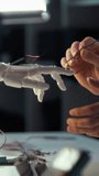 In high-tech workshop bathed in evening light, an engineer carefully solder-connects wires to a robotic hand prototype, fine-tuning its circuitry as precision and innovation drive the nocturnal build - Powered by Shutterstock - Get 15% off with code: PIKWIZARD15