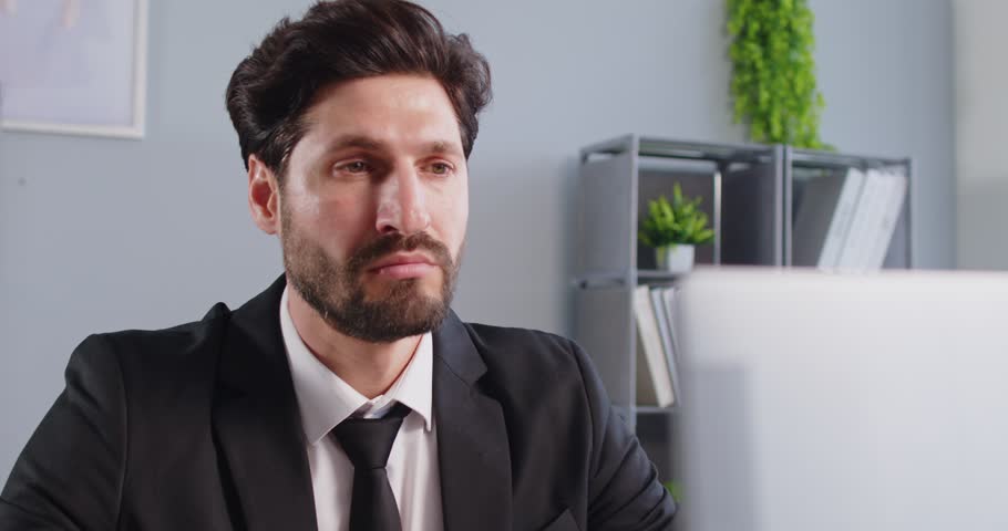 Businessman working in office setting, drinking beverage from mug, looking at laptop screen, working, attending virtual meeting, concentrated company worker, employed in new business project 