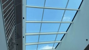 Bright skylight atrium blue sky glass ceiling framing serene modern interior curved white walls, metal railings and recessed LED lights, - Powered by Shutterstock - Get 15% off with code: PIKWIZARD15