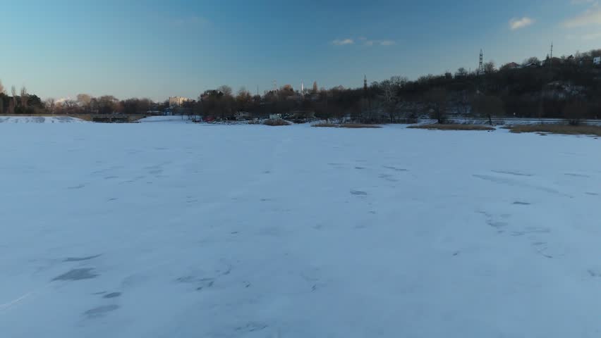 Snow-covered landscape with frozen river and distant trees under a clear blue sky, showcasing gradual changes in the scenery across three frames