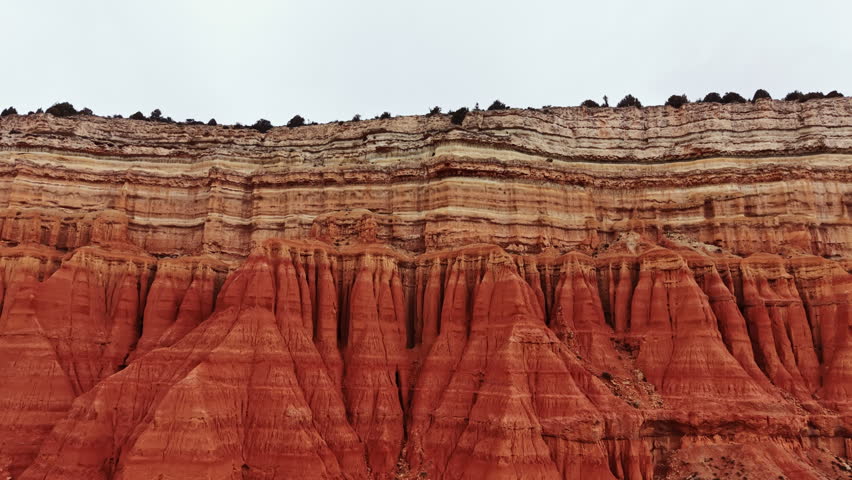 Visitors explore a canyon with large red rock formations. The rocky layers display different colors and patterns from erosion. The view captures the vastness of the canyon.