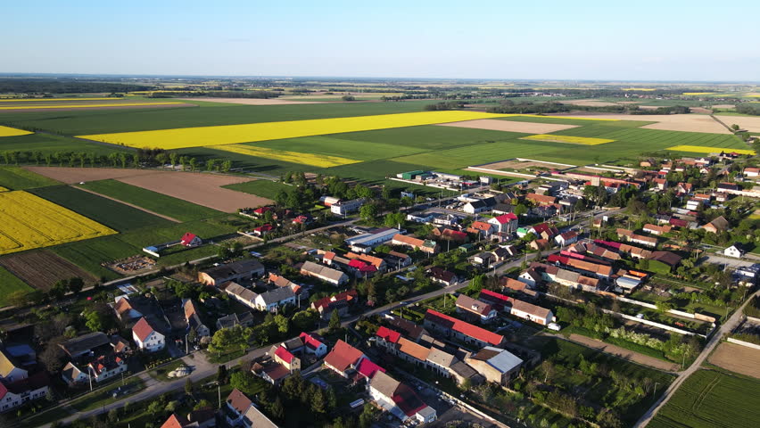Aerial view of rural village surrounded by green and yellow agricultural fields in Poland. Concept of countryside, farming, land use and rural landscape.