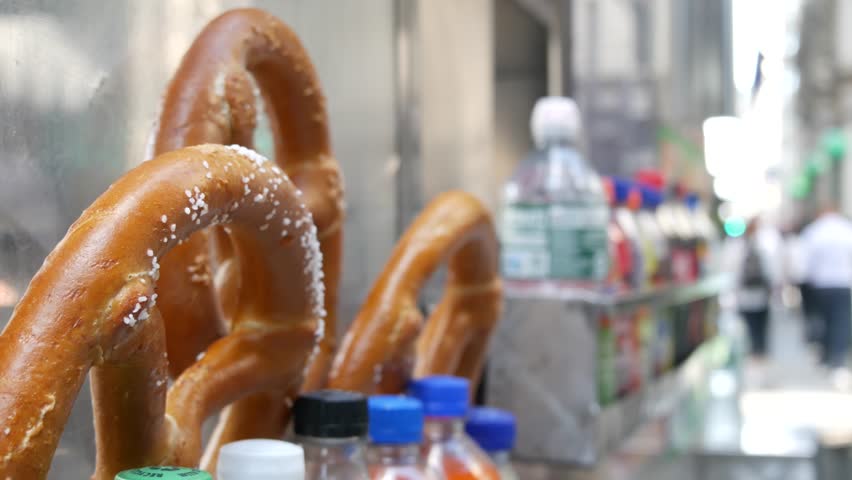 Pretzel for sale, street food in Manhattan, New York City, United States. Fast food counter, stall or kiosk, traditional pastry snack and soda drinks to go in NYC. Baked bread dessert, food on the go.