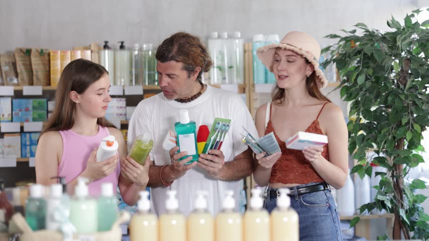 Man with wife and teen daughter customers in drugstore choose with different products. Parapharmacetical products, French body care cosmetic, pills and medicines are in drug store assortment
