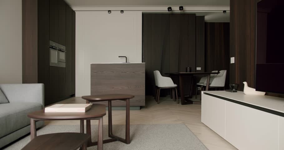 Stylish and modern minimalist living room featuring an open kitchen design, elegant wooden furniture, and tasteful decor in a cozy and inviting atmosphere.
