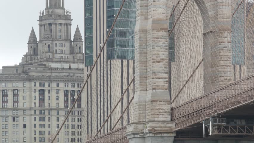 Brooklyn Bridge and Manhattan Municipal Building 1914 in Downtown from Brooklyn Dumbo, New York City Civic Center, United States. American brick architecture, famous tourist landmark. Foggy rainy day.