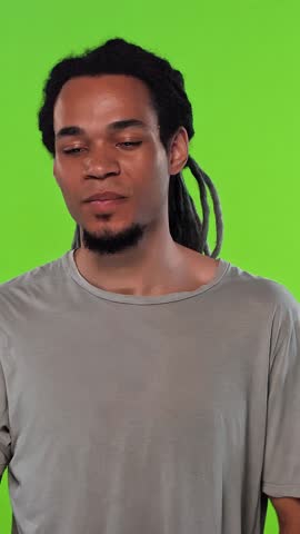Young African American man with dreadlocks expressing different emotions and giving thumbs up gesture in front of green screen background studio portrait