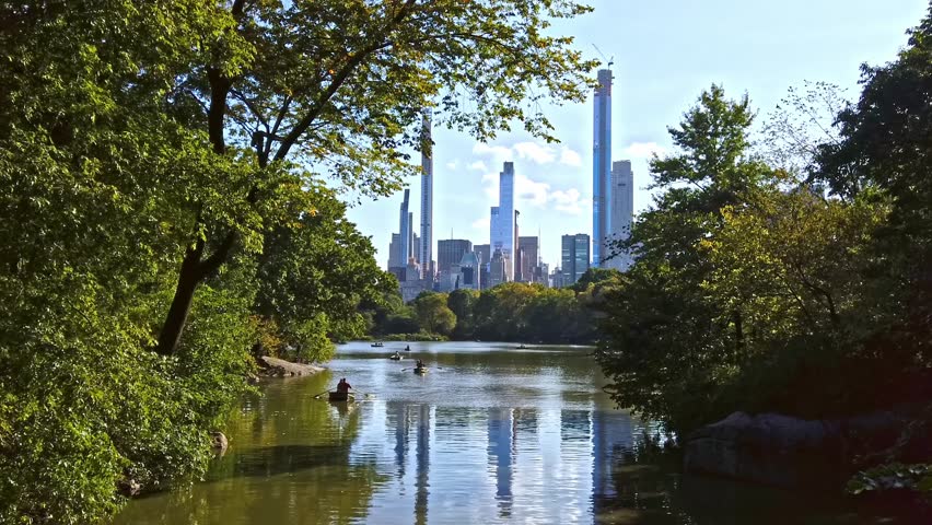 Boating on central park lake with cityscape skyline reflection cinematic footage motion.