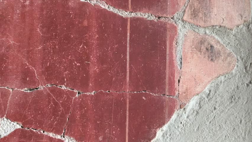 Herculaneum excavations featuring characteristic Pompeian red frescoes, showcasing vivid Roman wall paintings preserved by the eruption of Mount Vesuvius in Italy.