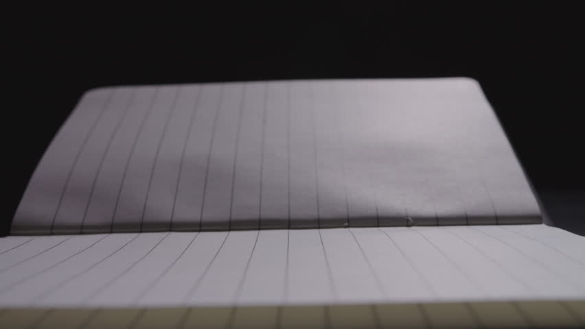 Close up of a pencil being laid down on an open notebook