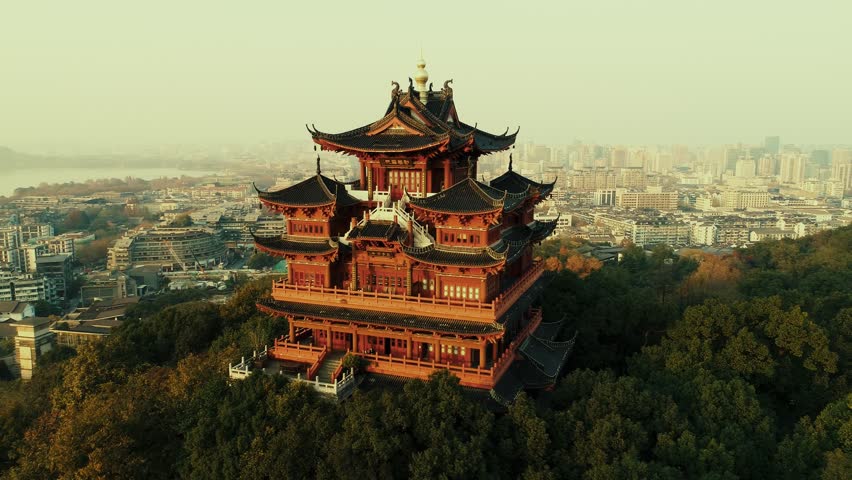 Hangzhou, China. Aerial view of traditional Chinese pagoda in cityscape during golden hour, with city skyline in the background.