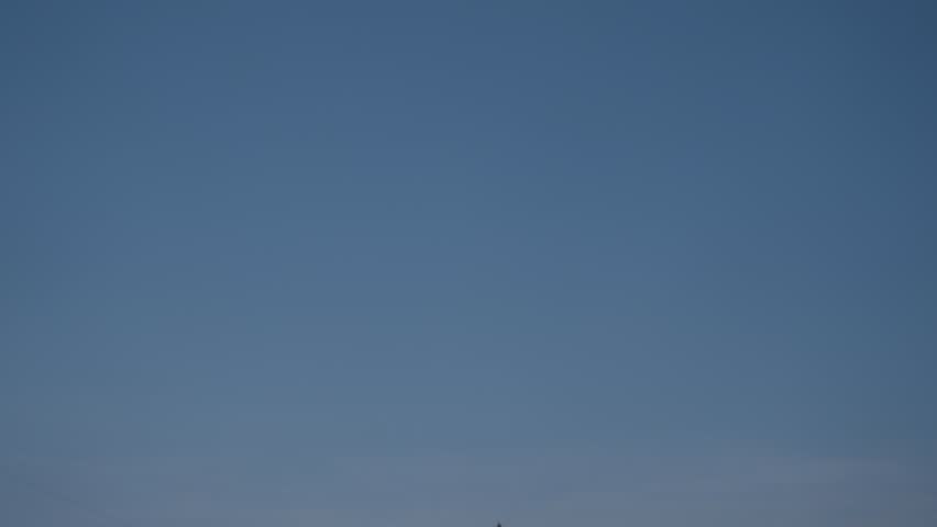 Pan Down From Blue Sky to Working Oil Rig in Dry Grassy Field in Oklahoma 