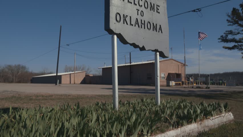 Pan Up on Gray Concrete Engraved Welcome to Oklahoma Sign at State Border 