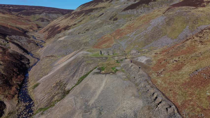 Hikers traverse scenic Gunnerside Gill in Yorkshire Dales, England