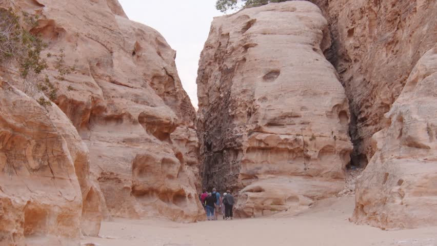 Senior tourist group walking in Little Petra sandstone canyon Jordan guided tour travel adventure ancient Nabataean landscape