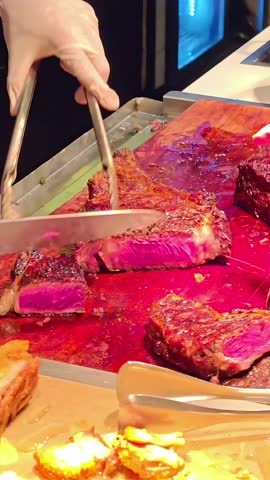Butcher chef slicing cutting a beef ribeye steak cut on wooden cutting board, BBQ Meat, Buffet Feast Dinner, Meal Preparation