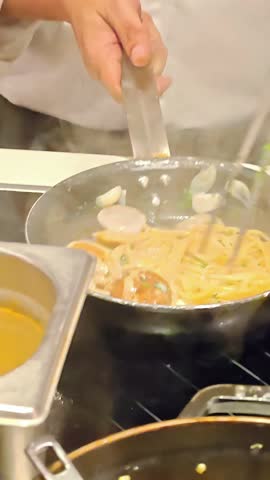 Chef tossing cooking creamy clam sauce spaghetti in frying pan, Italian Pasta Seafood Dish, Restaurant Kichen Setting