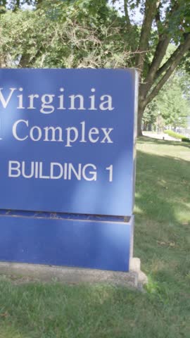 Vertical cinematic shot of West Virginia Capitol sign with government building in background and natural daylight outdoor setting