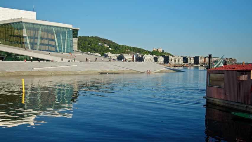 Oslo Opera House with reflection in harbor water in Oslo. Scenic waterfront and contemporary architecture during summer in Norway.